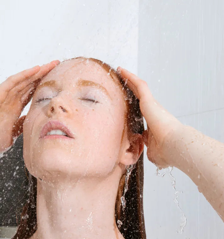 A person conditioning their hair with natural conditioner