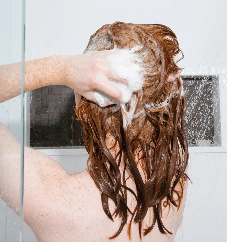 A person in the shower washing her fine hair with organic shampoo that works.