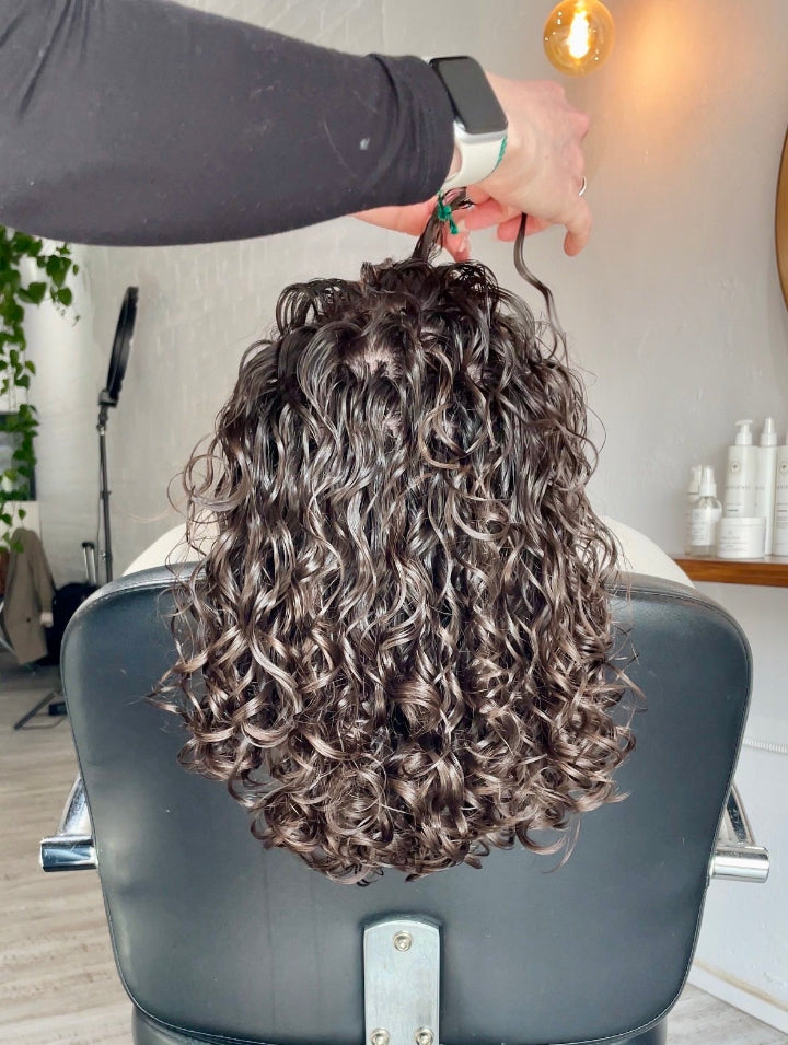 Person styling curly hair in salon.