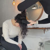 A hairstylist detangling curly hair before styling.