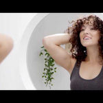 Learn how to hydrate coarse or curly hair in this video about clean beauty hair tips and using the Innersense Hydrating Hair Masque - cover photo is of a woman with curly hair smiling into the mirror