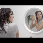 Video on how to set and style unmanageable curly hair like a pro hair stylist - organic hair hacks - cover photo is a woman with wet curly hair styling her hair in the mirror